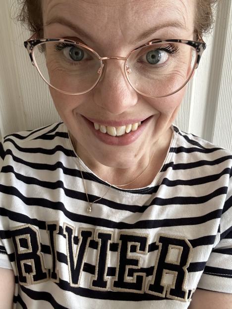 Close-up selfie of a woman wearing glasses and a striped shirt with