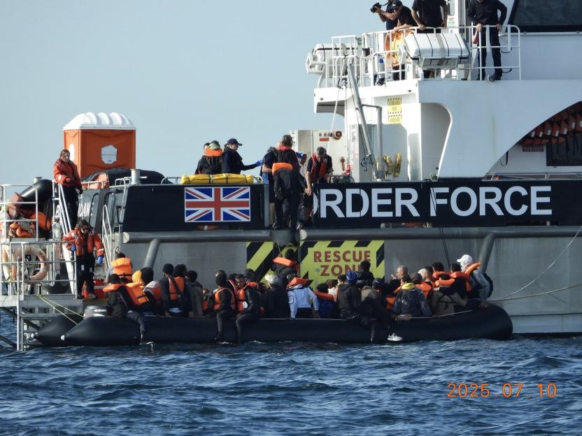 Migrants in a small boat being rescued by a Border Force vessel.