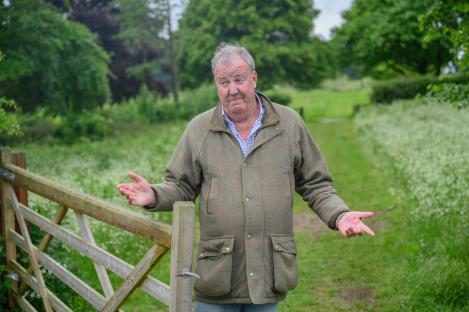 Jeremy Clarkson standing by a wooden gate with his arms outstretched.