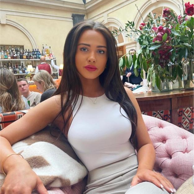 Woman in white top sitting in a chair.