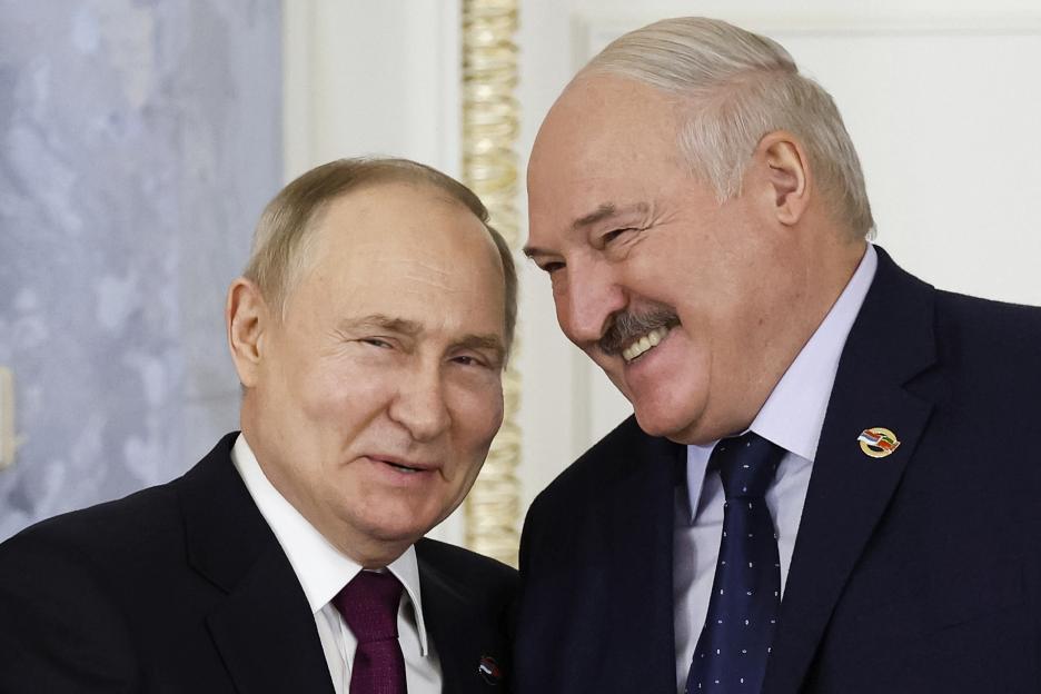 two men in suits and ties are smiling and one has a pin that says ' russia ' on it
