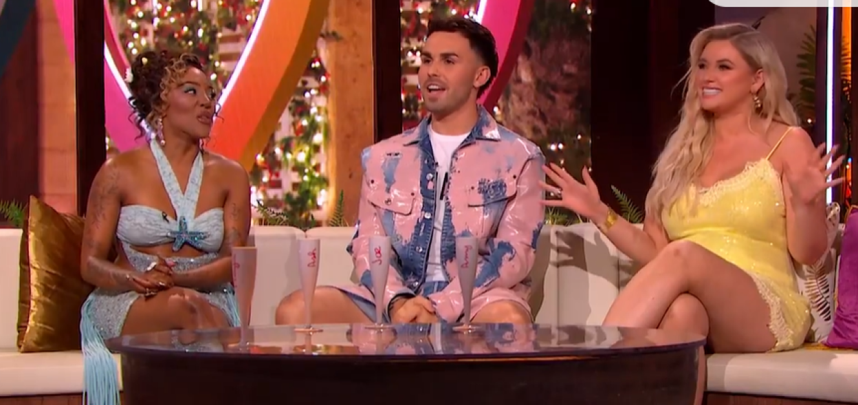 Screenshot of three people sitting on a couch and talking.
