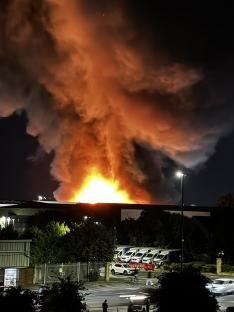 Large fire engulfing a warehouse at night.