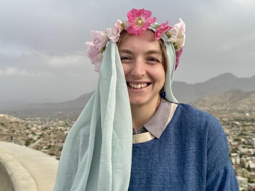 Smiling woman wearing a flower crown and light blue scarf.