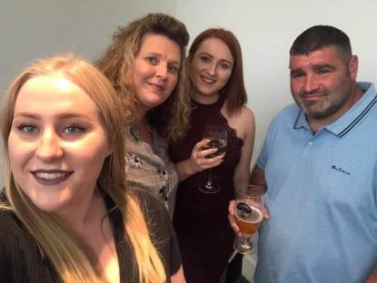 Group photo of four people holding drinks.