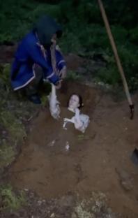 Police rescuing a woman buried in a hole during a raid of a Russian forest ceremony.