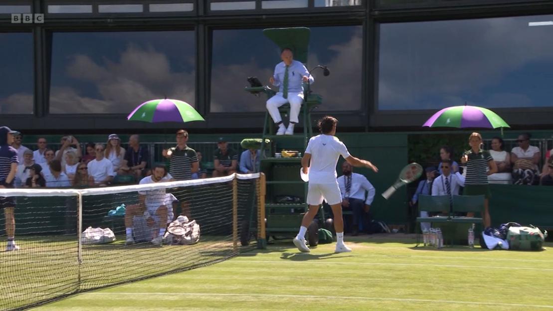 A tennis player throws his racket during a Wimbledon match.