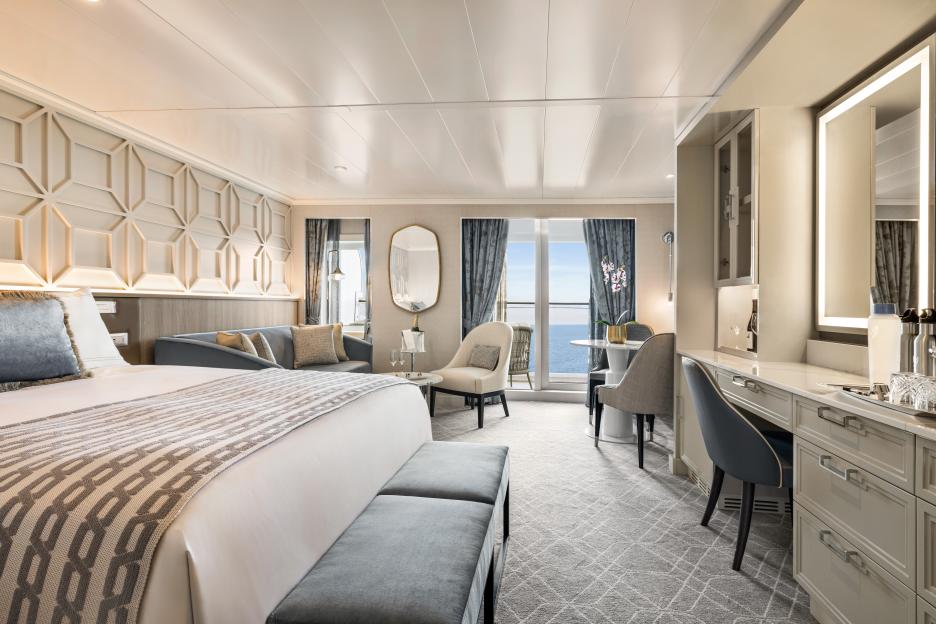 Ocean view cruise ship stateroom with bed, sofa, and desk.