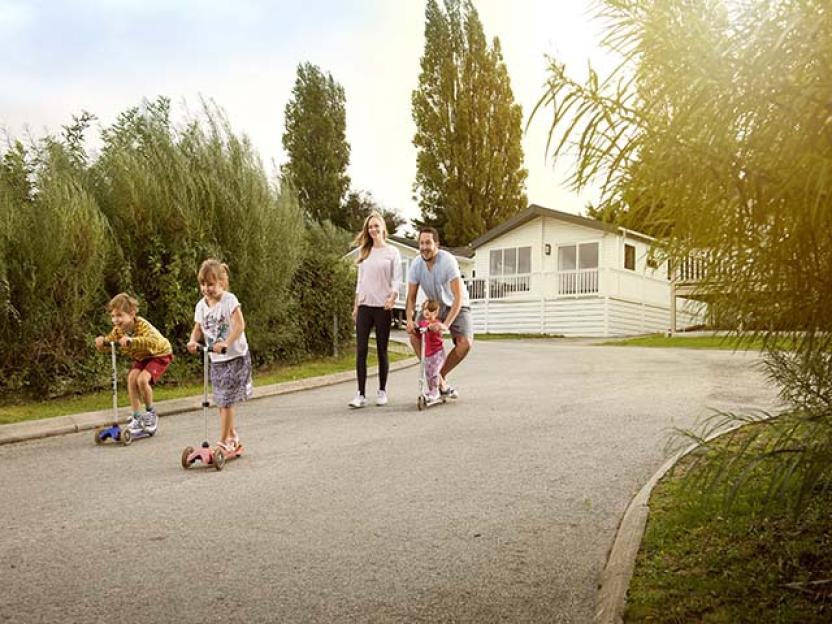 a family is riding scooters down a street in front of a house .