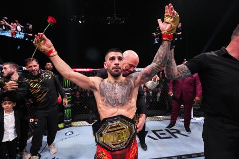 Ilia Topuria of Spain celebrates a knockout victory, holding a rose and the UFC featherweight championship belt.