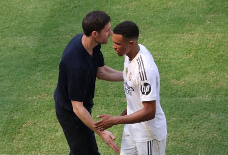 Trent Alexander-Arnold and Xabi Alonso shaking hands on a soccer field.