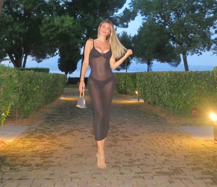 Woman in sheer black dress walking down a path.
