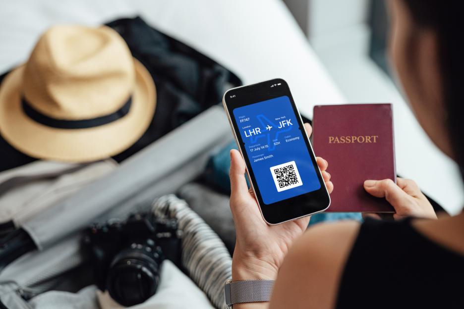 Woman holding phone displaying digital flight ticket and passport.