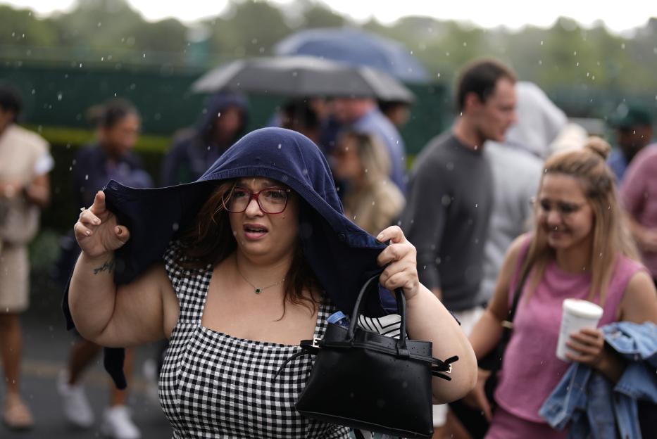 Spectator shielding herself from the rain at Wimbledon.