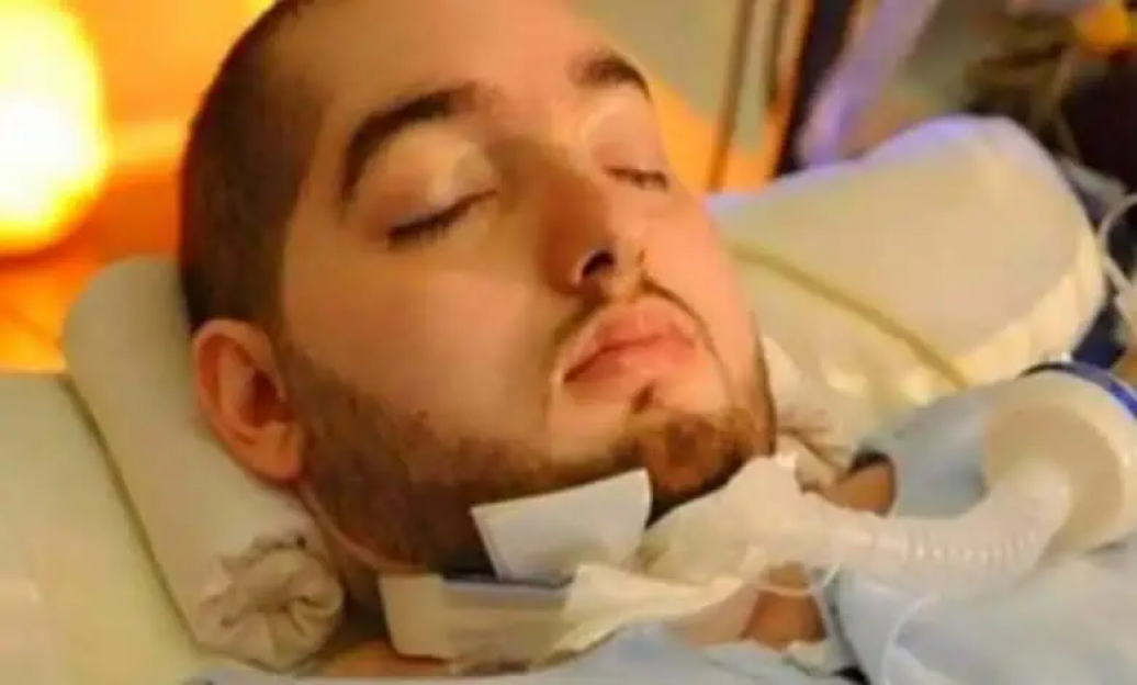 Man lying in a hospital bed, eyes closed.