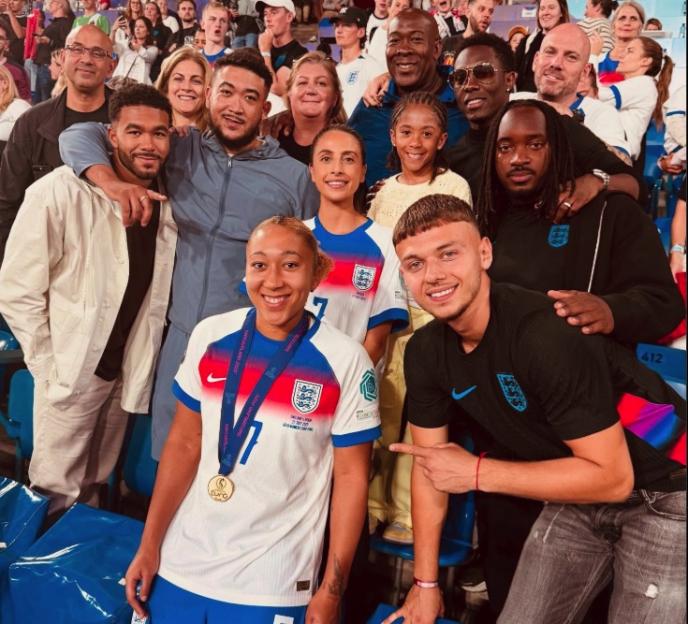 Group photo of a female soccer player with a gold medal and other people.