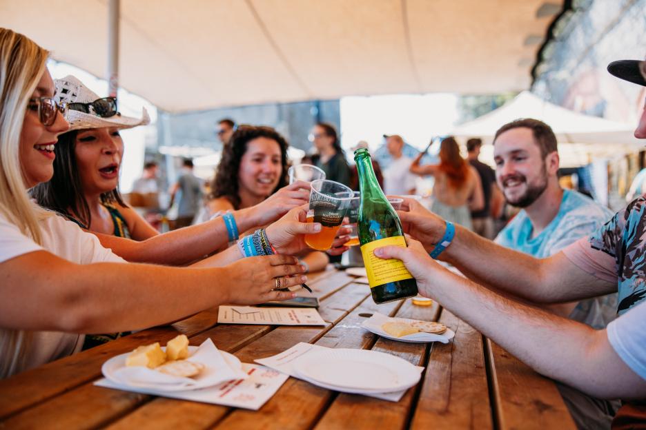 Friends toasting drinks at a summer food festival.