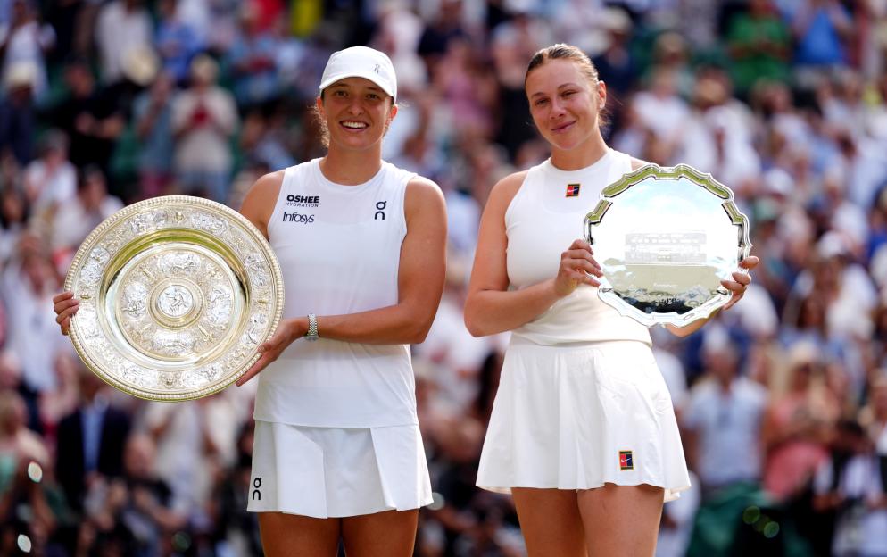 Iga Swiatek and Amanda Anisimova holding Wimbledon trophies.