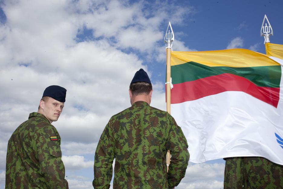 Lithuanian soldiers standing at attention with their flag.