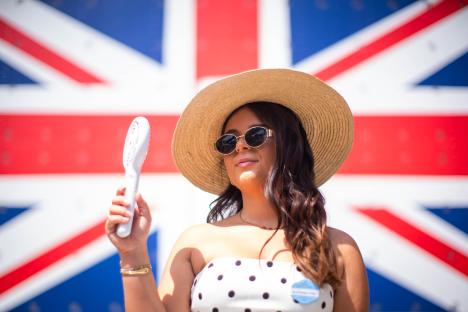 Woman uses handheld fan in front of a UK flag.