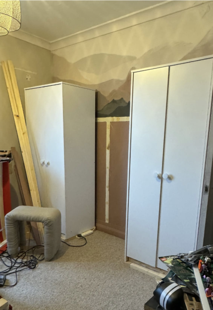 Two white wardrobes being assembled in a room.