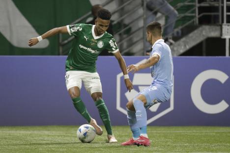 Soccer player in green vying for the ball with a player in light blue.