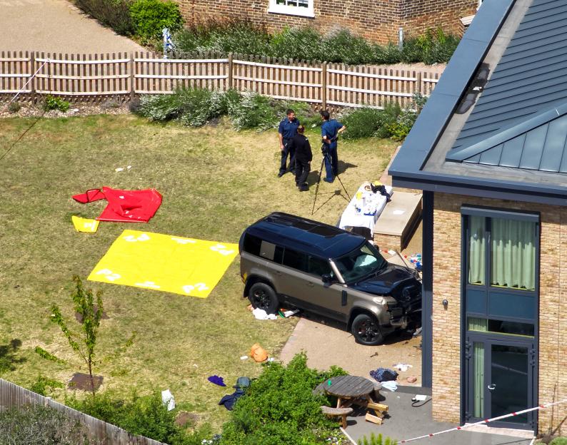 Aerial view of a Land Rover that crashed into a fence at a school, with police officers at the scene.