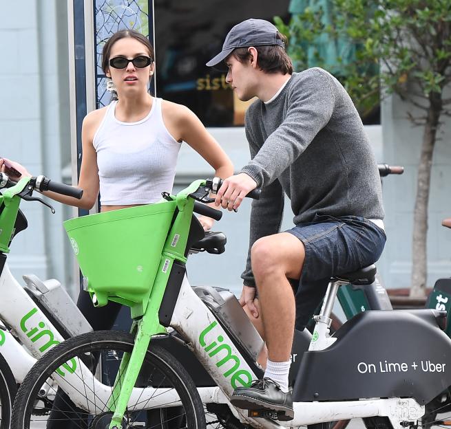 Olivia Rodrigo and Louis Partridge riding Lime bikes.