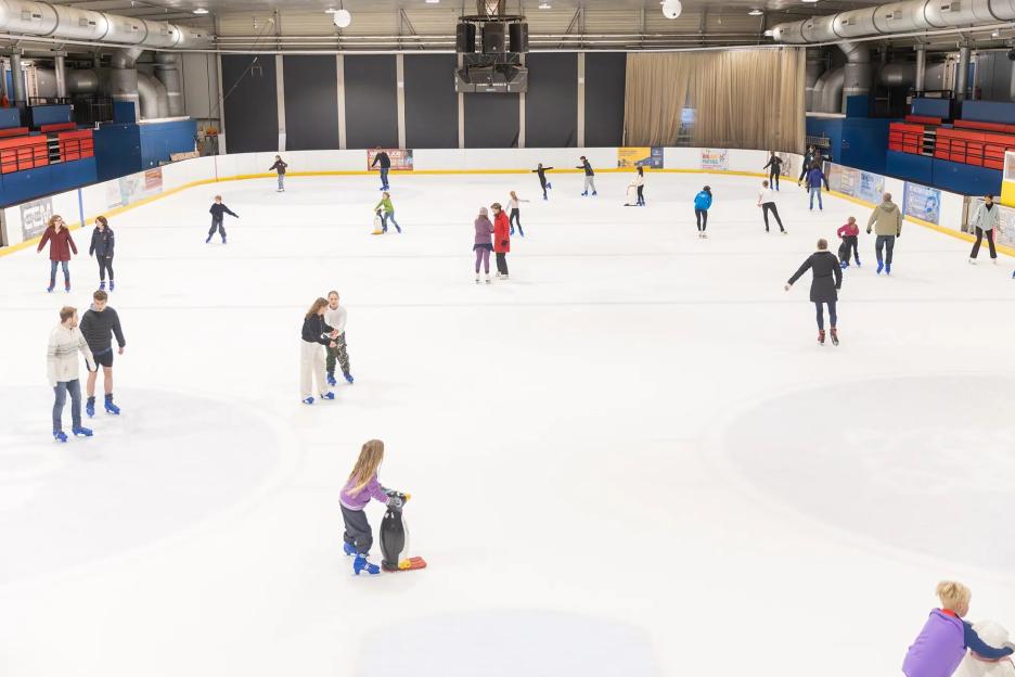 People ice skating at an indoor rink.