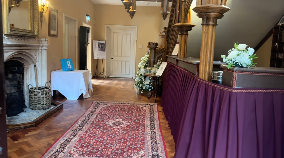Interior view of a building's entrance with a reception desk, a fireplace, and a rug.