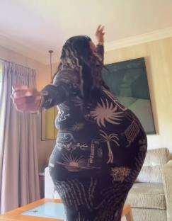 Alison Hammond in a patterned dress, arms outstretched.