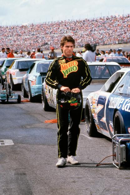 Tom Cruise in a Mello Yello racing suit at a race track.