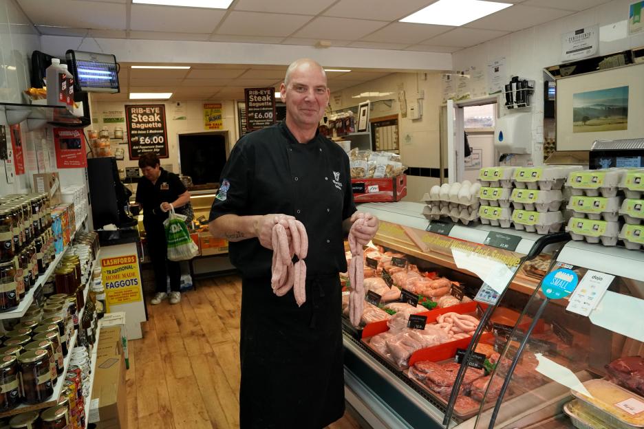 Butcher holding sausages in his shop.