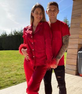 Charlotte and Kieran Trippier holding hands, wearing matching red pajamas.