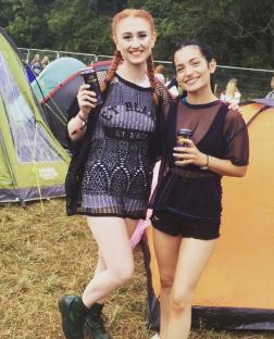 Two women at a festival, one holding a can of drink.