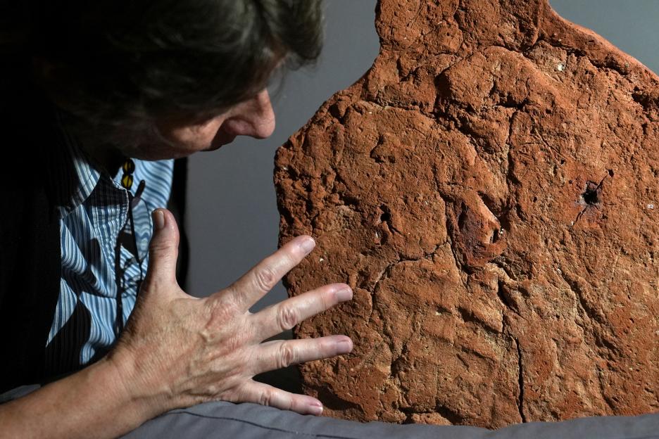 Curator examining a 4,000-year-old ancient Egyptian handprint on a soul house.