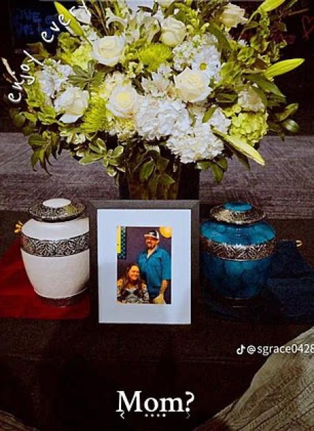 Two urns, a framed photo of a couple, and a floral arrangement.