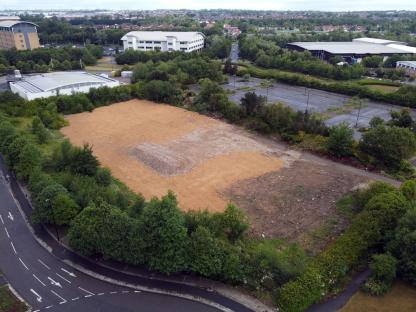 Aerial view of a cleared lot near a shopping center and hotel.