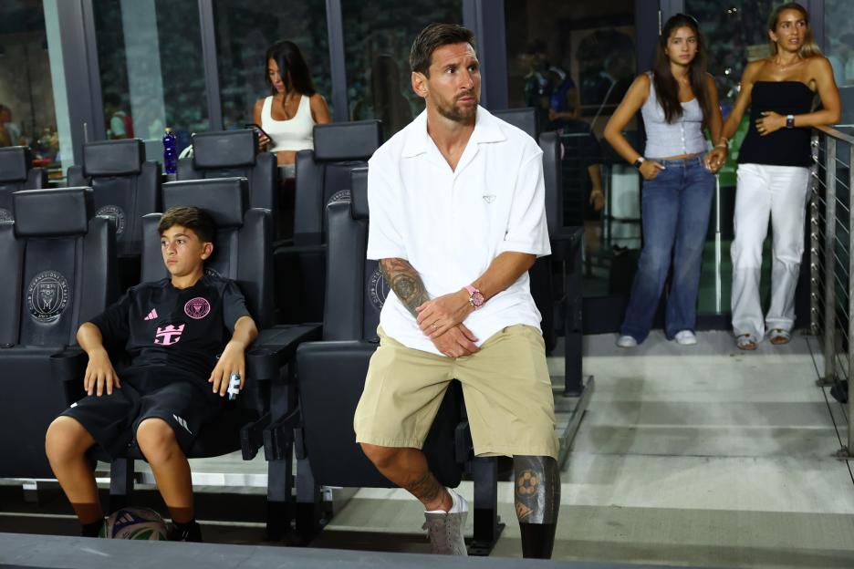 Lionel Messi and his son Thiago sitting in stadium seats.