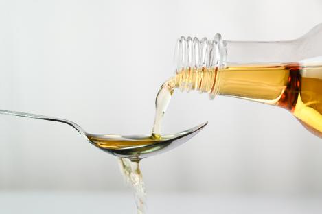 Apple cider vinegar pouring into a spoon.