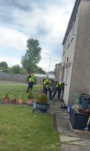 Police officers struggling to break down a door.