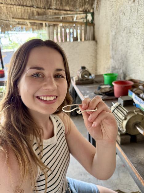 Woman holding a silver piece of jewelry she made in Bali.