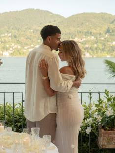 Couple embracing on a balcony overlooking a lake.