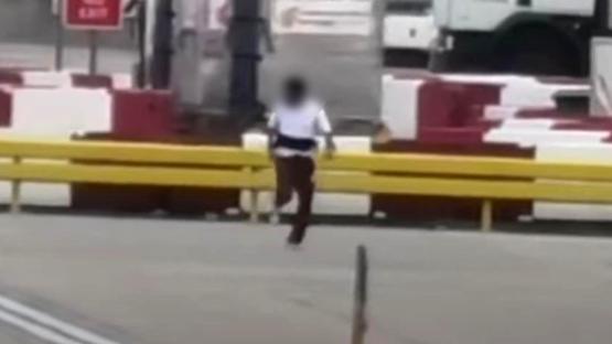 A man running on an airport tarmac being chased by several other men.