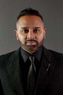 Portrait of a man in a black suit and tie.