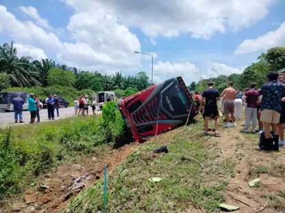 Bus on its side in a ditch; people standing nearby.