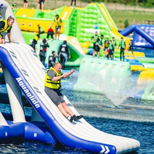 Man sliding down inflatable water slide at aqua park.