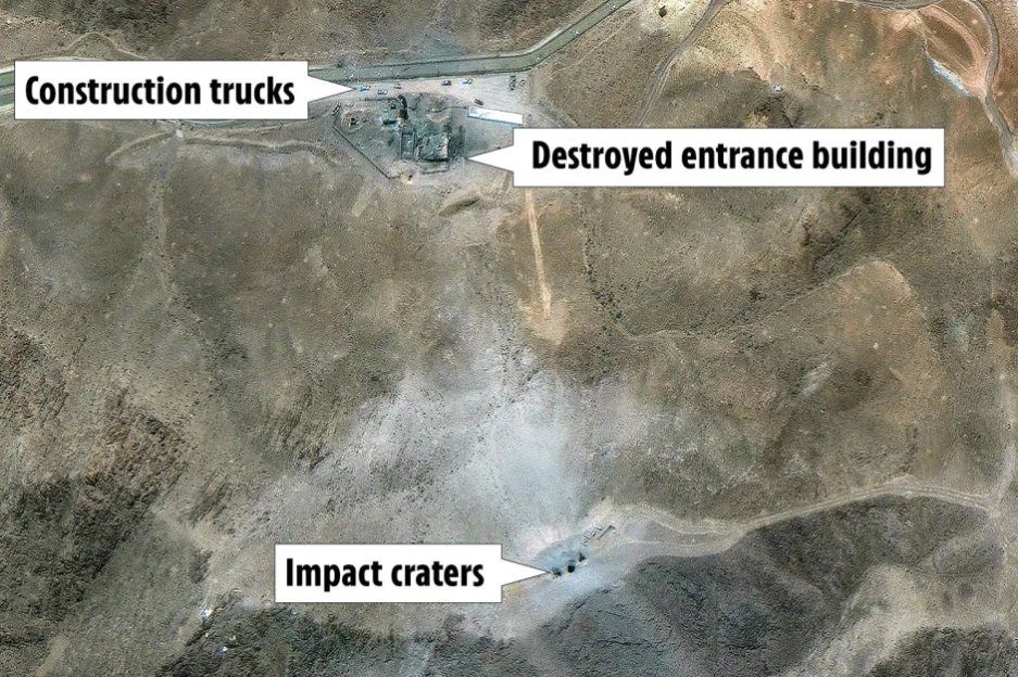 Aerial view showing impact craters, a destroyed entrance building, and construction trucks.