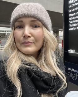 Woman with blonde hair wearing a grey hat.