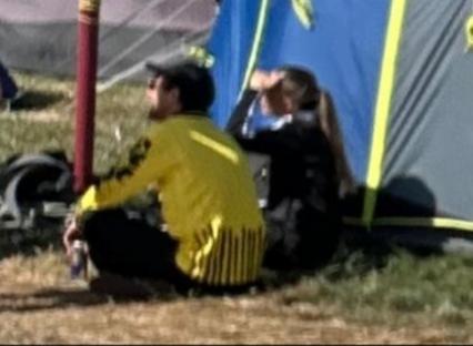 People sitting near tents at a festival.